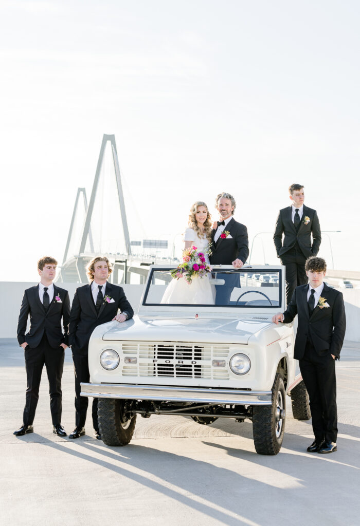 Family posing on 1966 Ford Bronco Roadster with Ravenel Bridge in the background for a wedding anniversary in Charleston