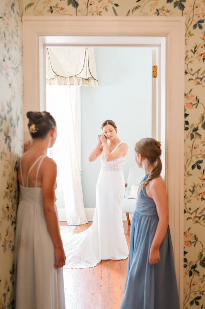Bride getting ready and putting on earrings at the beginning of a wedding photography timeline at Legare Waring House in Charleston, SC.
