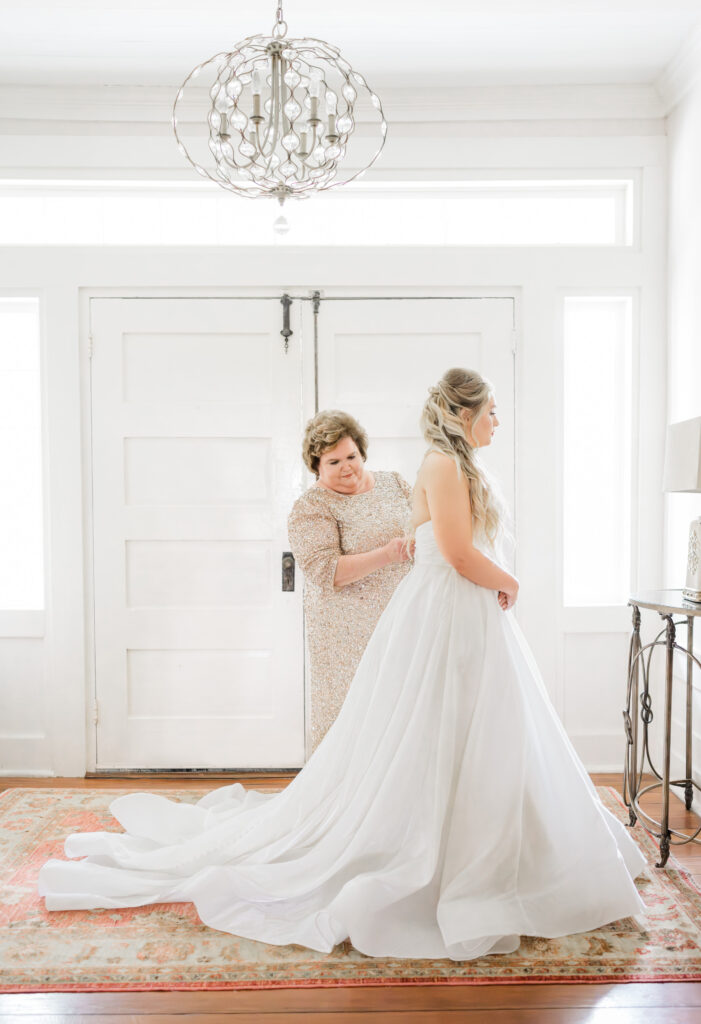 Mother zipping bride's dress at the beginning of a wedding timeline at Tanglewood Plantation, SC. 
